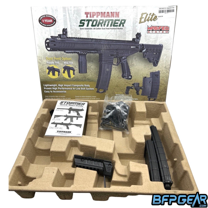 The packaging of the Stormer Elite. Cardboard mold fits spare magazines, marker, and marker accessories. Included are an adaptor for a hopper, spare parts, barrel squeegee, barrel sock, Allen keys, and a user manual.