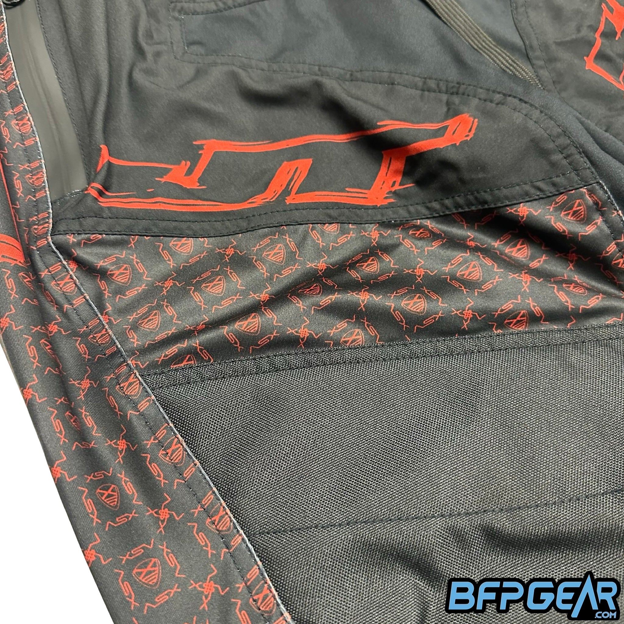 An up close shot of the pattern found on the XSV 24 JT Pro Joggers. The XSV Shield is surrounded on each side by XSV, all done in red.