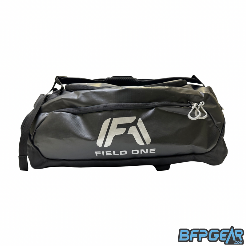 A side photo of the Field One AW Backpack. The backpack is black with a grey Field One logo in the center of the side. 
